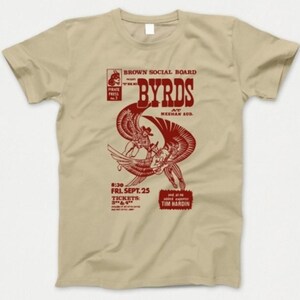 Op de afbeelding: Beige t-shirt met een rode afbeelding die een concert van "The Byrds" aankondigt. Het ontwerp bevat de bandnaam, gestileerde figuren en de tekst: "Brown Social Board", "At Meehan Aud" en "Fri. Sept. 25".