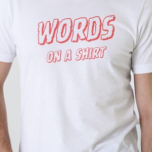 May include: White t-shirt with the words "WORDS ON A SHIRT" printed in red.