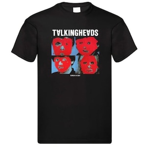 May include: Black t-shirt with the band name "TALKINGHEADS" in white above a graphic of four red faces on a blue background. The text "PERSON IN LIGHT" is below the graphic. A classic music-themed tee.
