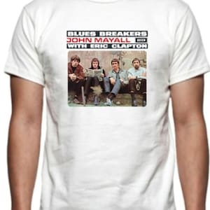 May include: White t-shirt featuring a graphic of the Blues Breakers with John Mayall and Eric Clapton. The graphic shows four men seated, with text above them. The shirt is a classic crew neck.