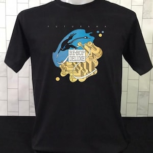May include: Black t-shirt with a graphic design featuring the word "FUTURAMA" at the top. The graphic includes a blue and yellow design with the words "BE-BOP DELUXE". The shirt is short-sleeved and made of a soft material.