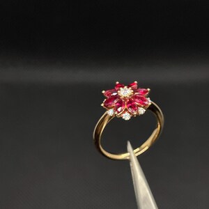 May include: A gold ring with a red ruby and diamond flower design.