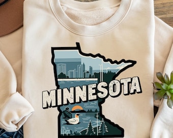 May include: A beige sweatshirt featuring a graphic print of the state of Minnesota. The graphic includes the state's outline, a cityscape, and the word "Minnesota" in a distressed font. The graphic is in shades of blue, black, and white.