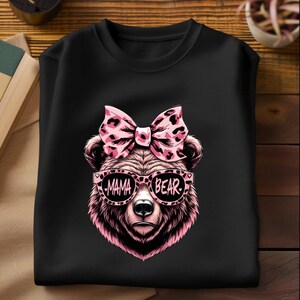 Pu&ograve; includere: Maglietta nera con un orso rosa che indossa occhiali da sole rosa che dicono "Mama Bear" e un fiocco rosa con stampa leopardata.