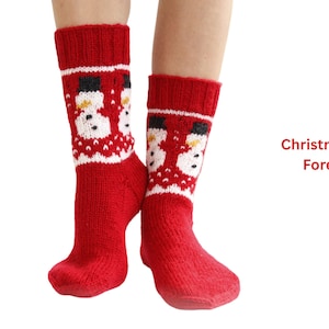 Puede incluir: Calcetines rojos de punto con diseño de muñeco de nieve. Los calcetines presentan un patrón de muñeco de nieve blanco y negro sobre un fondo rojo. El texto "Christmas in Forest" es visible.