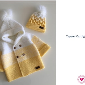 May include: A knitted baby cardigan and matching beanie in white and yellow. The hooded cardigan has wooden buttons and a small label. The beanie has a pom-pom on top. The text "Tayson Cardigan" is visible.