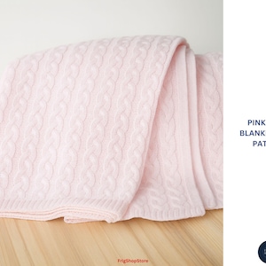 May include: A soft pink cable knit blanket. The blanket is folded and draped, showcasing the intricate woven pattern. The text "PINK CABLE BLANKET - KNIT PATTERN" is visible on the right side of the image.