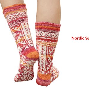 May include: A pair of knee-high socks with a Nordic pattern. The socks feature a vibrant color palette of red, orange, and white, with geometric and floral designs. The text "Nordic Sun Love" is visible on the right side.