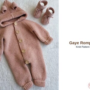 Könnte beinhalten: Hellrosa gestrickter Baby-Strampler mit Kapuze und passenden Babyschuhen. Der Strampler hat eine Knopfleiste und Holzknöpfe. Auf der Kapuze befinden sich kleine Ohren. Der Text "Gaye Romper Knitt Pattern" ist sichtbar.