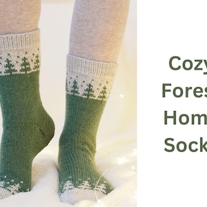 May include: A pair of green and white knit socks with a forest tree pattern. The socks have a light green body and a white cuff and toe with a repeating tree design. The text "Cozy Forest Home Socks" is visible.