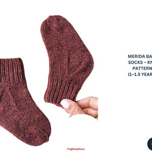 May include: Two knitted baby socks in a reddish-brown hue. The socks are displayed on a white background. The text "MERIDA BABY SOCKS - KNIT PATTERN (1-1.5 YEARS)" is visible. The socks are made of a soft, textured yarn.
