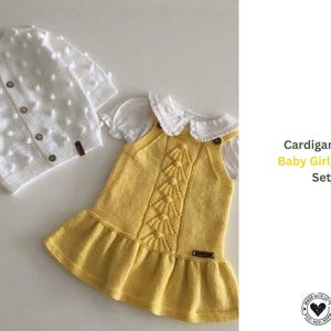Puede incluir: Un conjunto para bebé niña que incluye un cárdigan blanco tejido con detalles de bolitas y botones de madera, y un vestido amarillo tejido con cuello blanco y falda con volantes. El texto "Cardigan and Baby Girl Dress Set" está incluido.
