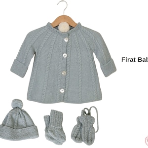 May include: A light blue knitted baby set, including a cardigan with button closures, a hat with a pom-pom, socks, and mittens. The set is displayed on a wooden hanger. The text "Firat Baby Set" is visible.