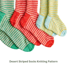Könnte beinhalten: Nahaufnahme von drei Paar gestrickten Socken in verschiedenen Farben. Ein Paar ist grün und beige gestreift, ein anderes rot und beige gestreift, und das letzte gelb und hellblau gestreift. Der Text "Desert Striped Socks Knitting Pattern" befindet sich unten.