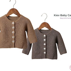 Puede incluir: Dos cárdigans de punto para bebé en marrón y gris cuelgan de perchas de madera. El cárdigan marrón tiene botones transparentes. El texto "Kiev Baby Cardigan" y "Baby Knitt Cardigans" es visible.