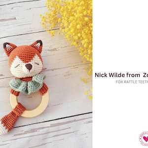 May include: A handmade crochet fox rattle teether with a wooden ring. The fox is orange and white with brown ears and a green collar. The text "Nick Wilde from Zootopia" is displayed.