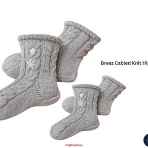 May include: Four pairs of light gray Breez Cabled Knit High Socks are displayed. The socks have a cable knit design with a floral embellishment near the top. The text "Breez Cabled Knit High Socks" is visible in the image.