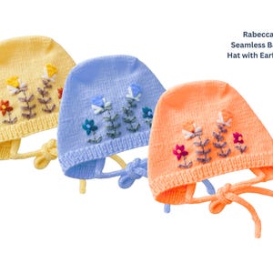Peut inclure: Trois bonnets de bébé tricotés en jaune, bleu et pêche, chacun orné de motifs floraux brodés. Les bonnets ont des cache-oreilles et des liens. Le texte de l'image indique "Rabecca Seamless Baby Hat with Earflaps."