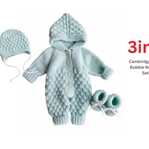 May include: A light blue knitted baby set, including a hooded romper, hat, and booties. The romper features a bubble stitch design and wooden buttons. The set is displayed on a white background. Text on the image reads "3in1 Cambridge Style Bubble Romper Set."