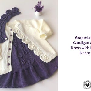 May include: A knitted baby outfit featuring a cream-colored cardigan with scalloped edges and a matching purple dress. The dress has a grape-leaf design and a ruffled hem. A matching headpiece is also included.