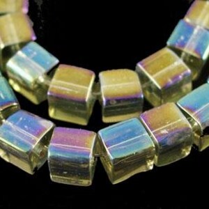 May include: Iridescent cube-shaped beads with a shimmering, multi-colored finish. The beads are strung together, showcasing their reflective surfaces and geometric form. The beads are approximately 0.25 inches in size.