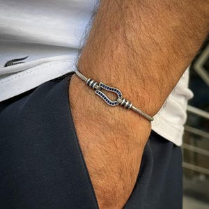 May include: A white ceramic mug with a black handle and the text "But First, Coffee" in a black, bold font. The mug is on a white surface. The mug is approximately 4 inches tall.