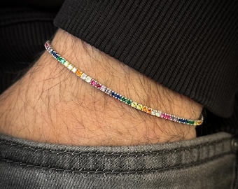 May include: A silver bracelet with a rainbow of colorful gemstones. The bracelet is thin and delicate, and the gemstones are set in a pave setting.