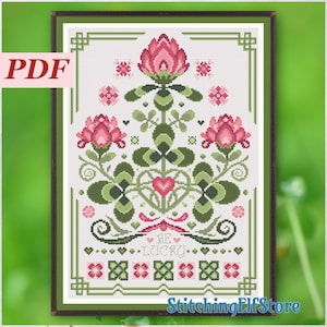 May include: Cross stitch pattern featuring a green four-leaf clover with pink flowers and the text "Be Lucky".