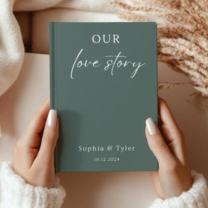 May include: A teal green hardcover journal with the text "OUR love story" in white script. The names "Sophia & Tyler" and the date "10.12.2024" are printed in white at the bottom.