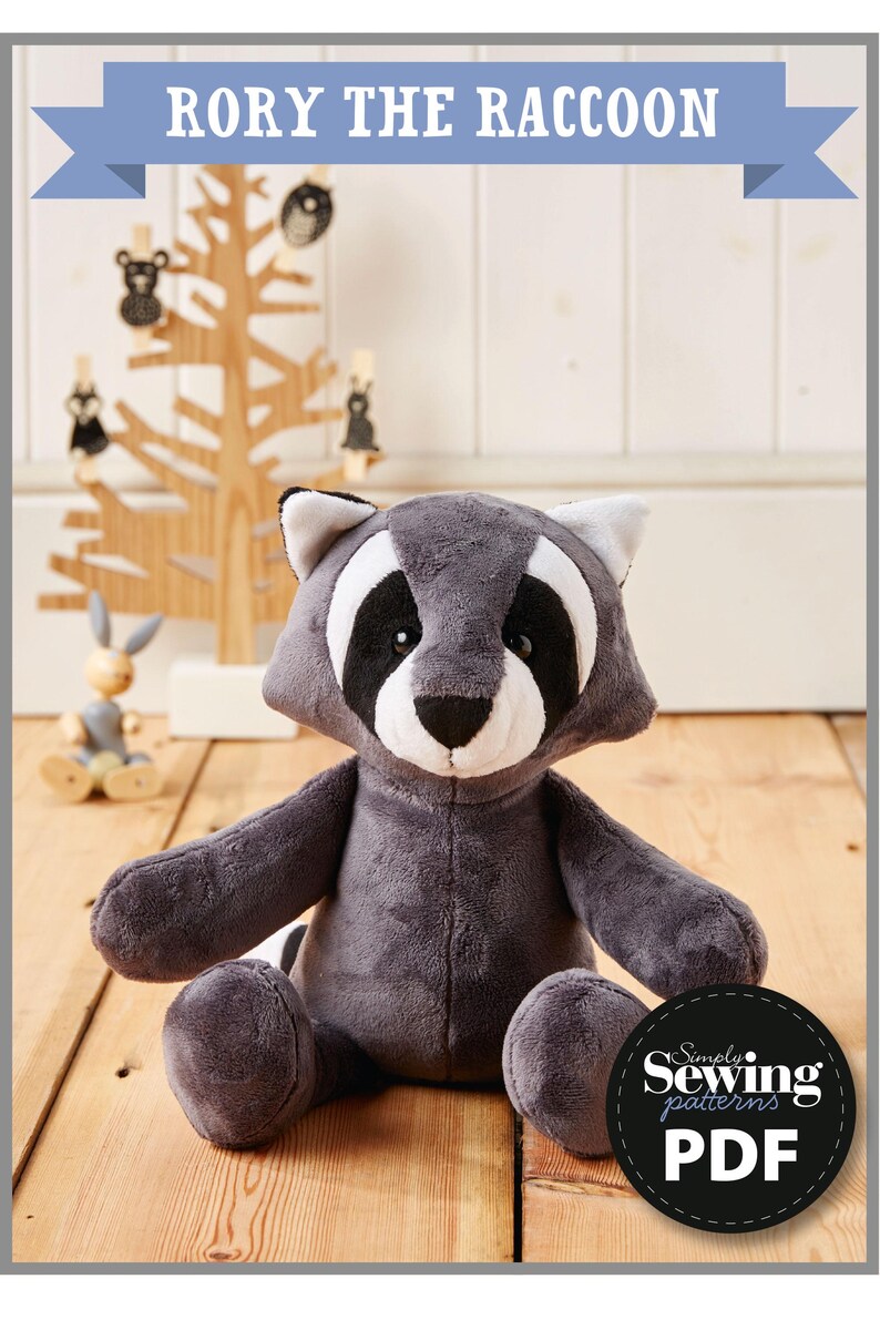 May include: A gray plush raccoon toy sitting on a wooden floor. The toy has black eyes, a black nose, and a white muzzle. The toy is wearing a black and white mask. The toy is sitting in front of a wooden tree with black and white animal ornaments. The image includes the text "Rory the Raccoon" and "Simply Sewing Patterns PDF".