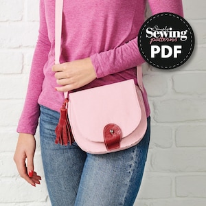 May include: A light pink crossbody bag with a curved flap and a red leather accent. The bag has a long strap and a red tassel. The bag is shown with the text "Simply Sewing patterns PDF" in a black circle.