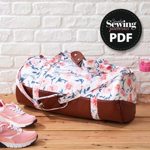 May include: A floral print duffel bag with brown leather accents and handles. The bag features a white background with pink and blue floral patterns. The image also includes a pair of pink sneakers and a water bottle. The bag has the text "Simply Sewing patterns PDF".