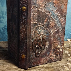 May include: A dark brown leather-bound book with a metal dragon design and the words "Time Machine" embossed on the cover.