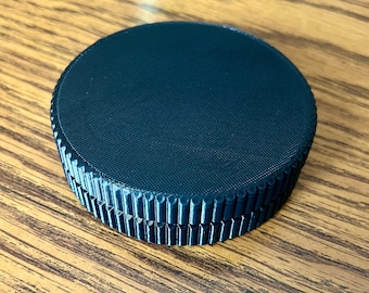 May include: A dark blue, round, plastic container with a textured top and a smooth bottom.