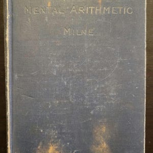 Puede incluir: Un libro de tapa dura azul con el título "Mental Arithmetic" y el nombre del autor "Milne" impreso en la portada.