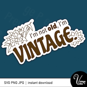 Puede incluir: Una pegatina blanca con texto marrón que dice "No soy viejo, soy VINTAGE". La pegatina tiene un diseño floral en el lado izquierdo.