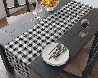 Puede incluir: Un camino de mesa a cuadros blanco y negro sobre una mesa de madera oscura con platos blancos y cubiertos.