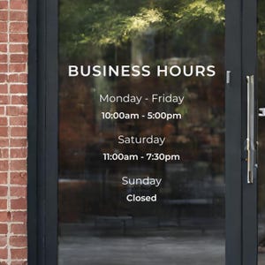 May include: A glass door with a sign that reads "BUSINESS HOURS" and lists the hours of operation for each day of the week. The hours are: Monday - Friday 10:00am - 5:00pm, Saturday 11:00am - 7:30pm, and Sunday Closed.