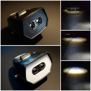 May include: A black and silver LED light with two lenses. The light is shown in a close-up shot, and also in use, illuminating a road at night. The light has a rectangular shape with a silver top and a black front.