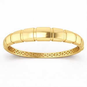 May include: A gold bangle bracelet with a segmented design. The bracelet features rectangular links and a honeycomb pattern on the inner band. The gold is bright and shiny. The bracelet is a piece of jewellery.
