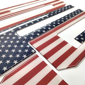 Könnte beinhalten: Satz mit fünf Türgriffabdeckungen für Autos im amerikanischen Flaggen-Design. Die Abdeckungen bestehen aus einem glänzenden Material und zeigen ein rot-weiß-blaues amerikanisches Flaggenmuster.