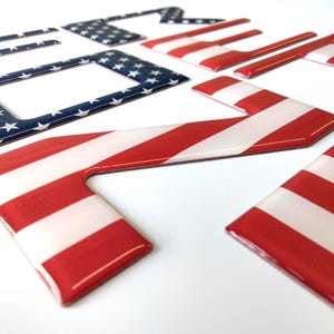 May include: A set of six red, white, and blue American flag-themed car decals. The decals are made of a glossy, durable material and feature a raised 3D design.
