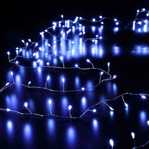 May include: A string of small, bright white LED lights on a thin silver wire, illuminated against a dark background. The lights are evenly spaced and emit a cool, blue-white glow, creating a festive or decorative effect. Suitable for holiday or event decor.