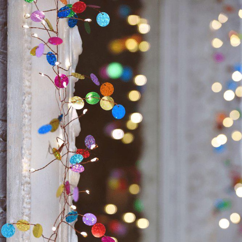 Puede incluir: Una guirnalda de luces decorativa con un fino cable de cobre entrelazado con peque&ntilde;os discos circulares brillantes de colores rojo, azul, verde, amarillo, morado y naranja, acentuada con diminutas luces LED de color blanco c&aacute;lido.