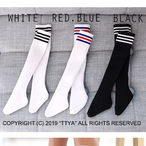 May include: Three pairs of knee-high socks in white, red and blue stripes, and black with white stripes.  The socks are on a gray couch.  The text "COPYRIGHT (C) 2019 "TTYA" ALL RIGHTS RESERVED" is below the socks.  A pair of white knee-high socks with black stripes are on a person's legs.  The text "COPYRIGHT (C) 2020 "TTYA" ALL RIGHTS RESERVED" is below the socks.