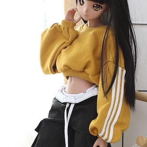 May include: A yellow cropped sweatshirt with white stripes on the sleeves. The sweatshirt has a relaxed fit and is made of a soft, comfortable fabric.