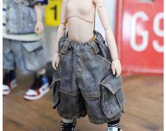 May include: A ball-jointed doll wearing loose-fitting gray denim cargo shorts with visible stitching, black and white high-top sneakers, and black and white striped socks. The doll has a pale, articulated body and is standing upright.