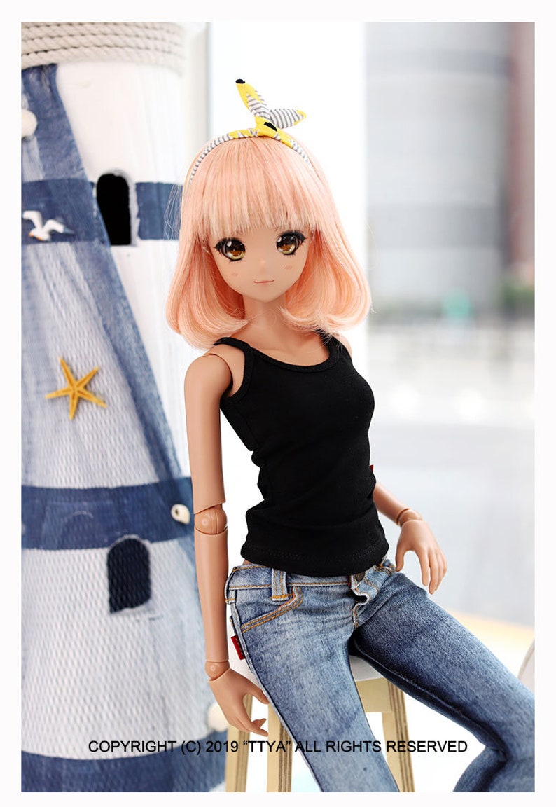 Puede incluir: Una mu&ntilde;eca con el pelo rosa que lleva un top negro sin mangas y unos vaqueros azules. La mu&ntilde;eca est&aacute; sentada en un taburete blanco. La mu&ntilde;eca lleva una diadema amarilla y blanca con un lazo en la parte superior.