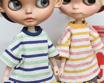 Puede incluir: Dos muñecas con camisetas a rayas. Una camiseta tiene rayas azules y verdes, la otra tiene rayas amarillas y rojas. La palabra "BLUE" está en la parte inferior izquierda y "YELLOW" en la parte inferior derecha.