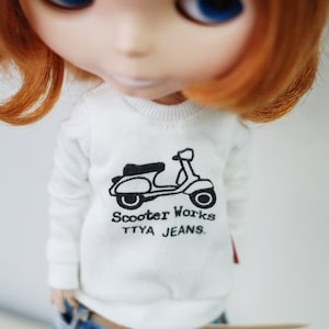 May include: A white long-sleeved shirt with a black and white graphic of a scooter and the text "Scooter Works TTYA Jeans."